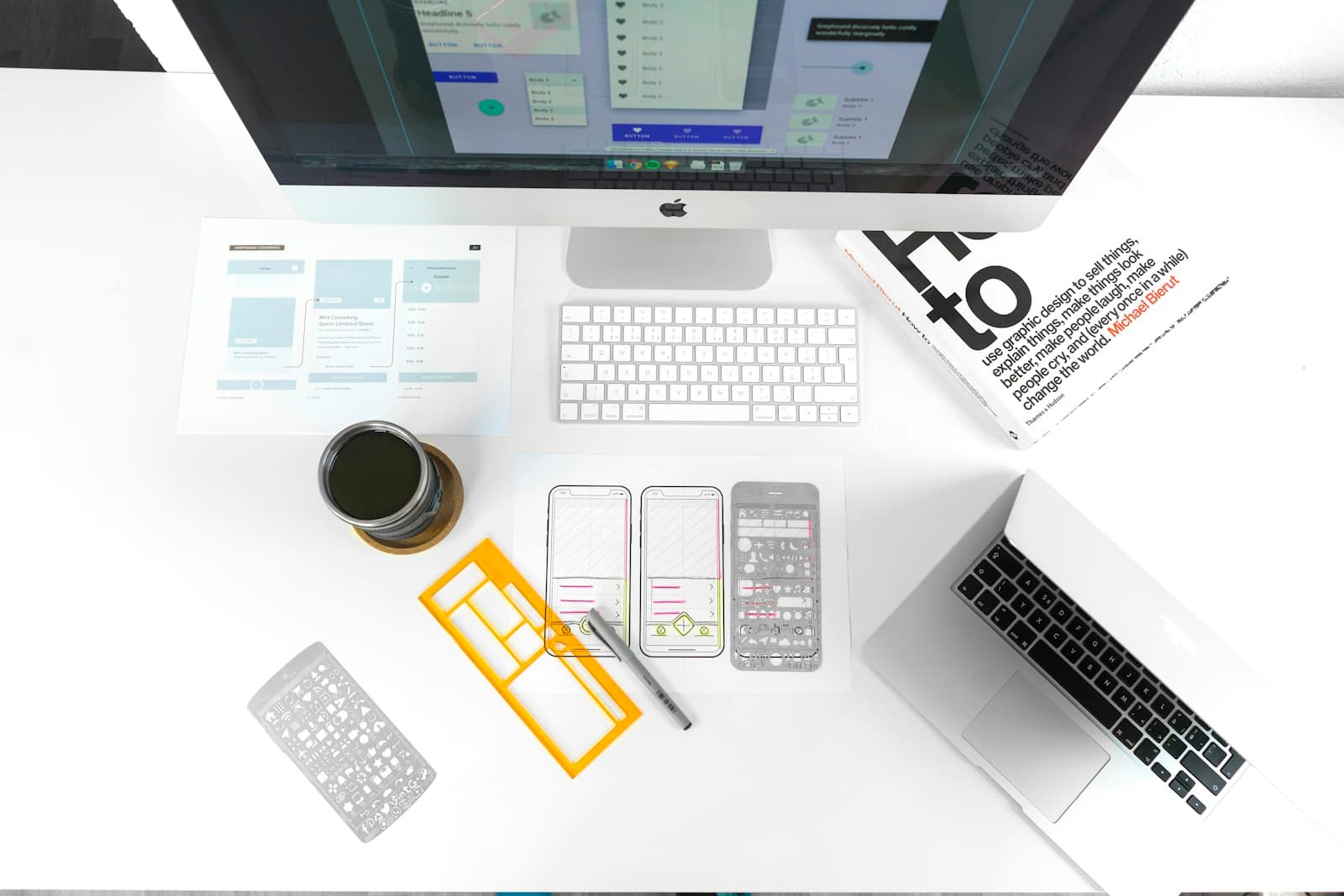 Een bureau met websiteontwerpen, wireframes en een computer